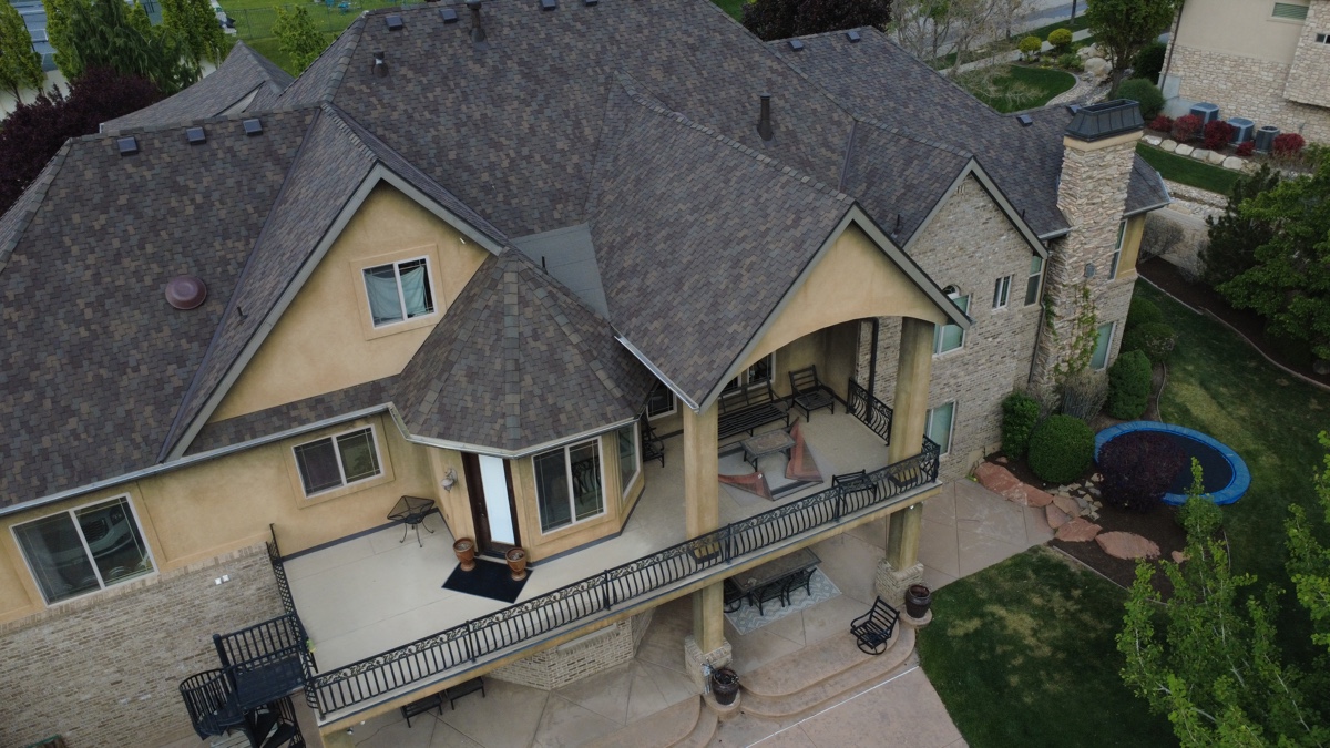 Close aerial of a craftsman luxury home with stone accents, balcony, and architectural shingle roof installed by Frame Restoration Utah, May 2026